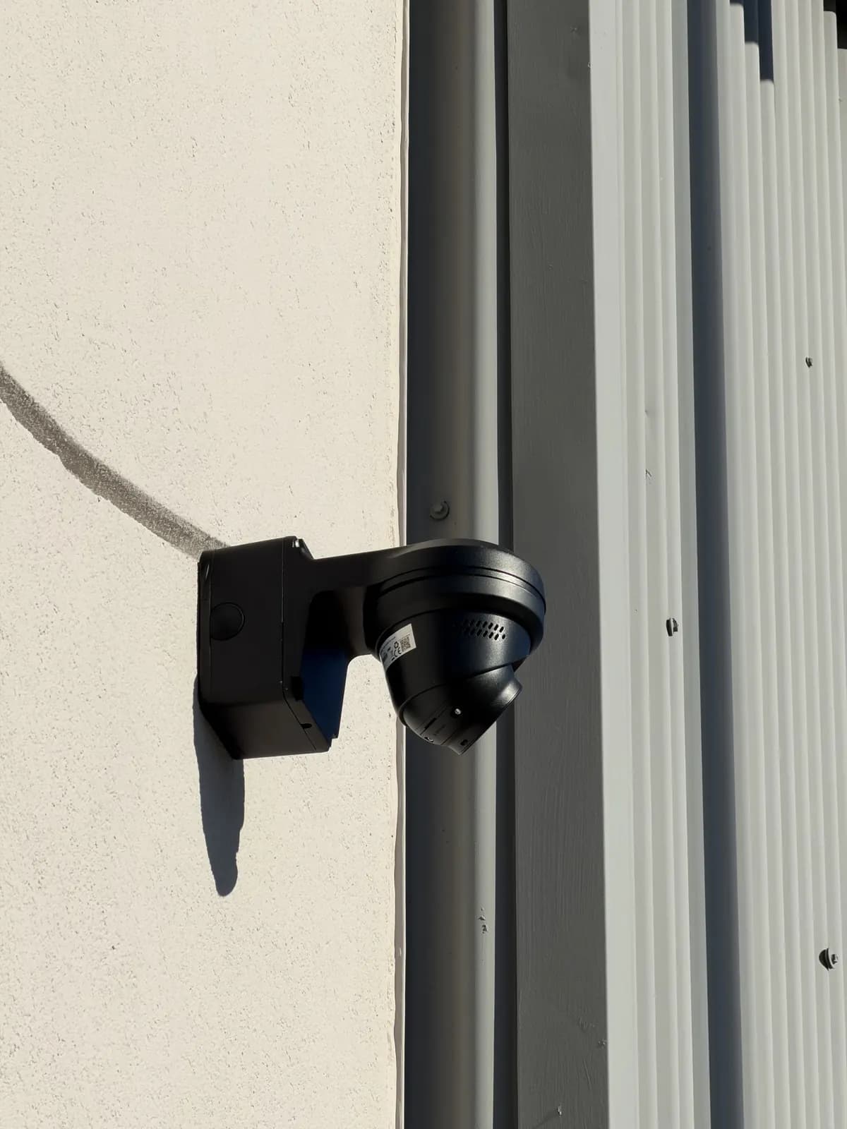 Black dome camera on a wall-mount bracket on a commercial building