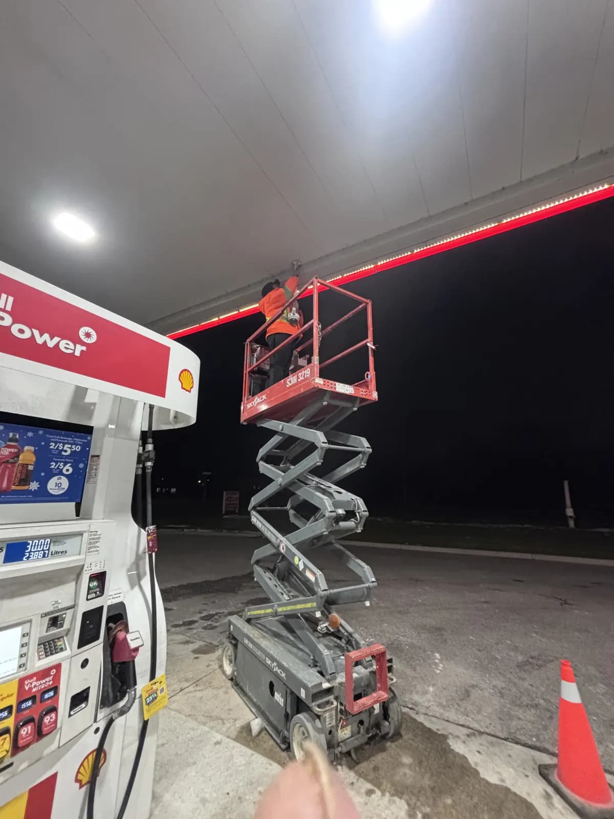 Scissor lift under a gas station canopy at night during a camera installation