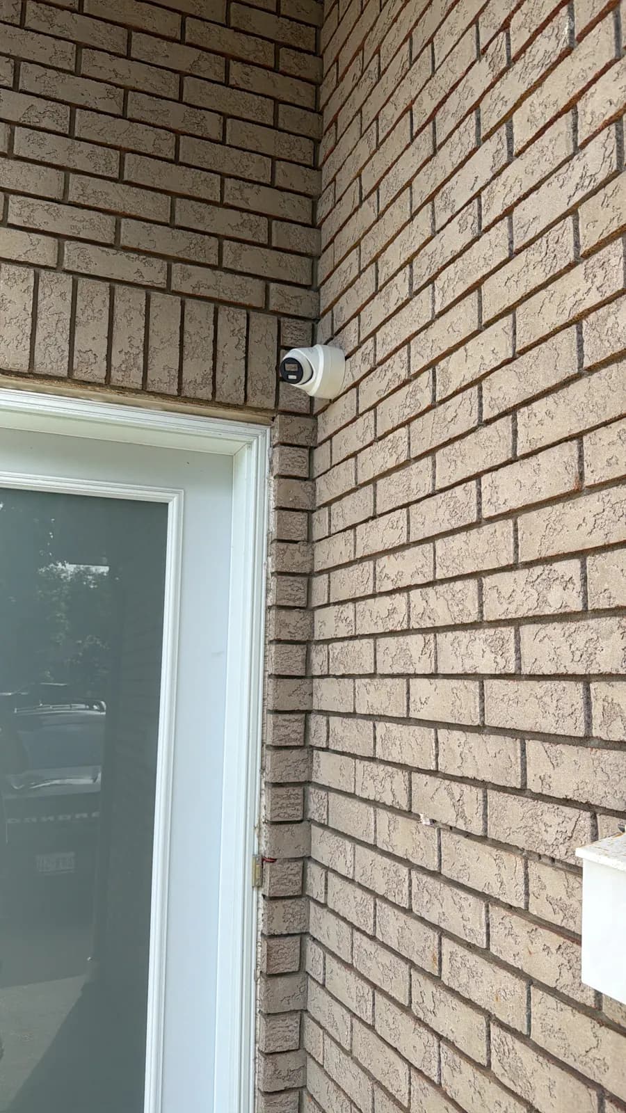 Turret security camera mounted above the back door of a brick house
