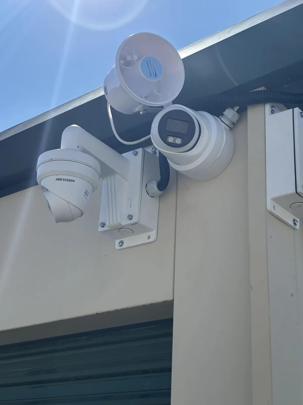Hikvision PTZ camera and turret camera on a wall bracket above storage unit doors